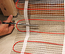 Cutting the mesh backing of the floor heating mat to make a turn.