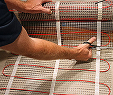Cutting the mesh backing of the floor heating mat.